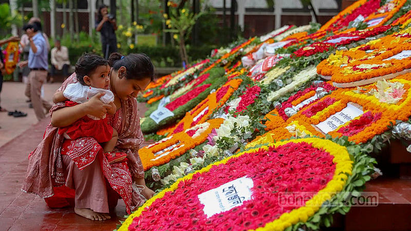 শিশু কোলে জাতীয় কবি কাজী নজরুল ইসলামের মৃত্যুবার্ষিকীতে শনিবার ফুল দিয়ে শ্রদ্ধা নিবেদনে এক নারী।
