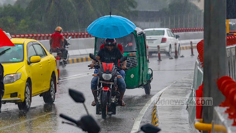 ঢাকার মেয়র হানিফ ফ্লাইওভারের উপরে সোমবার দুপুরের বৃষ্টি থেকে বাঁচতে মোটরসাইকেল আরোহী ধরে রেখেছেন ছাতা।