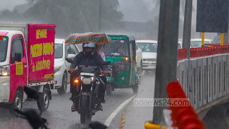 ঢাকার মেয়র হানিফ ফ্লাইওভারের উপরে সোমবার দুপুরের বৃষ্টি থেকে বাঁচতে মোটরসাইকেল আরোহী ধরে রেখেছেন ছাতা।