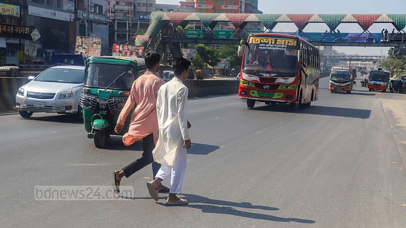 ঢাকার শনির আখড়া এলাকায় পাশেই ফুটওভার ব্রিজ রেখে ঝুঁকি নিয়ে সড়কের মাঝ দিয়েই পার হচ্ছেন পথচারী। ছবিটি জাতীয় নিরাপদ সড়ক দিবসের আগের দিন শুক্রবারের।
