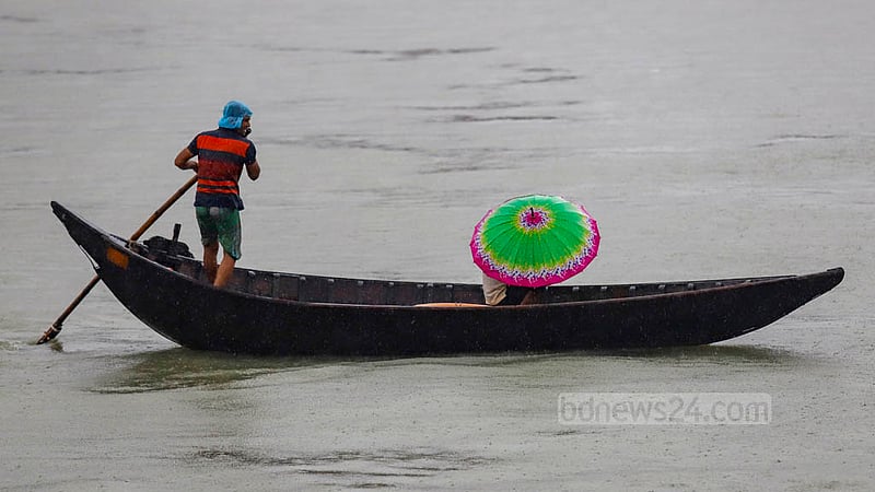 ঘূর্ণিঝড় সিত্রাংয়ের প্রভাবে বৃষ্টির মধ্যে সোমবার বুড়িগঙ্গা নদী নৌকা দিয়ে পার হচ্ছে মানুষ।