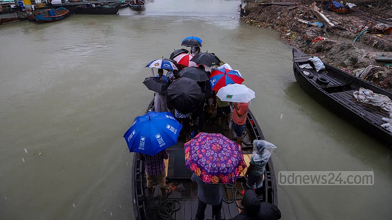 বৃষ্টির মধ্যে সোমবার ছাতা মাথায় বুড়িগঙ্গা নদী ট্রলারে পার হচ্ছেন মানুষ।