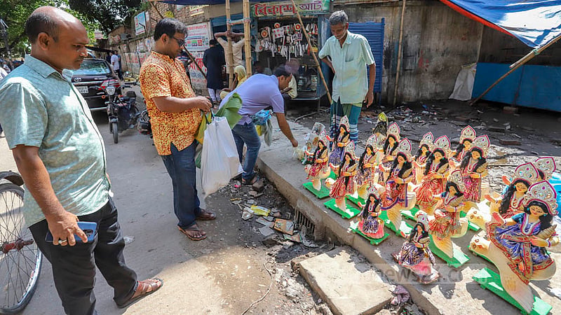 লক্ষ্মীপূজা উপলক্ষে শাঁখারী বাজারে লক্ষী প্রতিমা দেখছেন ক্রেতা।
