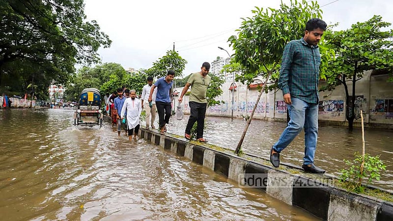 ঘূর্ণিঝড়ের বৃষ্টিতে ঢাকার নিউ মার্কেট এলাকার রাস্তায় জলাবদ্ধতা সৃষ্টি হওয়ায় মঙ্গলবার সকালে সড়ক বিভাজক দিয়ে যাতায়াতের চেষ্টায় পথচারীরা।
