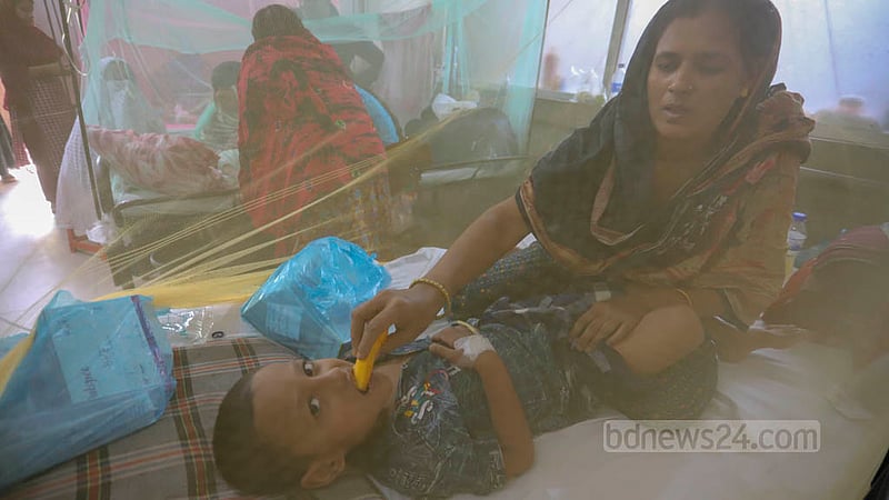 ঢাকার শিশু হাসপাতালে ডেঙ্গু জ্বরে আক্রান্ত এক শিশুকে মশারির মধ্যে খাবার খাওয়াচ্ছে মা।