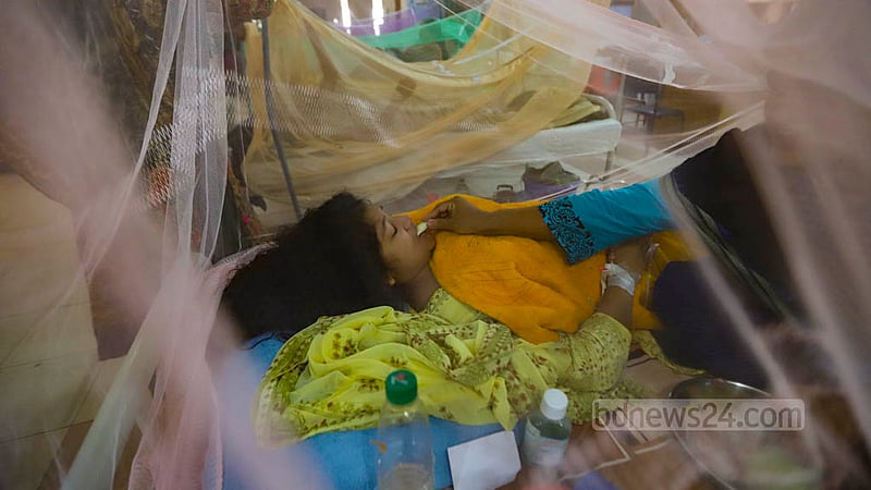 ঢাকার মুগদা মেডিকেল কলেজ হাসপাতালে ডেঙ্গু ইউনিটে রোববার মশারীর&amp;nbsp; মধ্যে এক রোগীকে ফল খাওয়াচ্ছেন স্বজনরা।