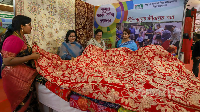 এসএমই পণ্য মেলার একটি স্টলে নকশি কাঁথা দেখছেন ক্রেতা।&amp;nbsp;ছবি: আসিফ মাহমুদ অভি