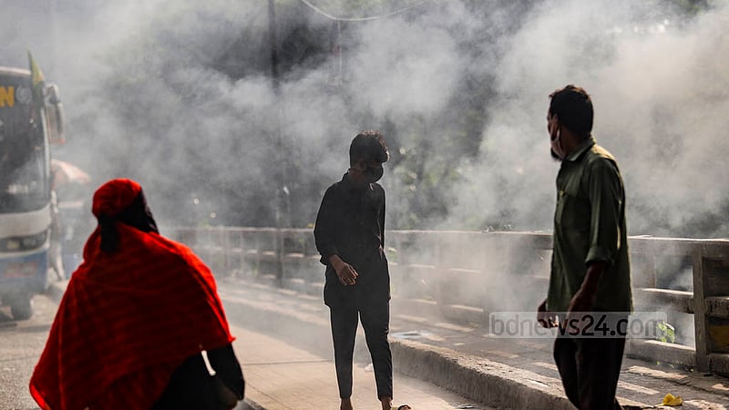 মুখে মাস্ক থাকার পরও বর্জ্য পোড়ানোর ধোঁয়ার মধ্য দিয়ে পথ চলতে মুখ চেপে ধরতে হচ্ছে পথচারীদের।