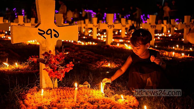 ঢাকার ফার্মগেইট হলি রোজারি চার্চের সমাধি ক্ষেত্রে মোমবাতি জ্বালিয়ে প্রিয়জনের শান্তি কামনায় এক শিশু।