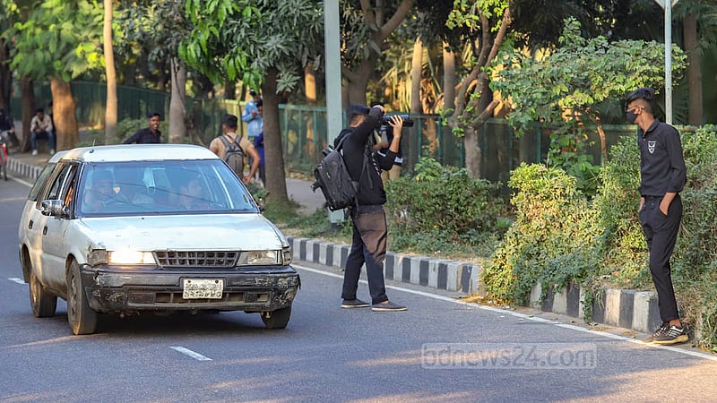হাতিরঝিলের ব্যস্ত সড়কে চলছে যানবাহন, তার মধ্যে ঝুঁকি নিয়ে দাঁড়িয়ে তোলা হচ্ছে ছবি।