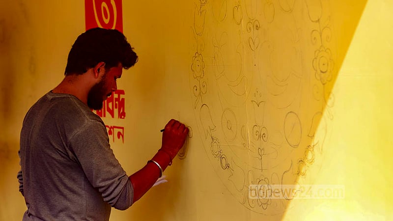ঢাকার সোহরাওয়ার্দী উদ্যানে অমর একুশে বইমেলায় অনেক স্টলের কাজ শেষের দিকে, এখন চলছে বর্ণমালা লেখার কাজ।&amp;nbsp;ছবি: মাহমুদ জামান অভি