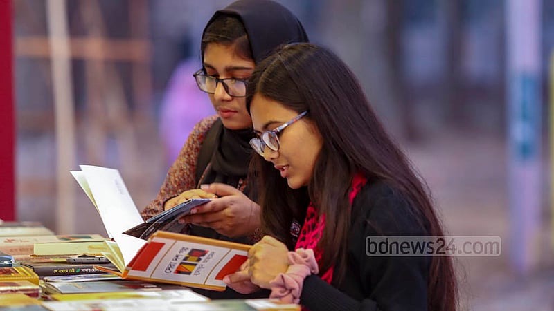 বইমেলার প্রথম দিন বুধবার সোহরাওয়ার্দী উদ্যানে মেলা প্রাঙ্গণে একটি স্টলে বই দেখছেন দুই তরুণী।ছবি: মাহমুদ জামান অভি
