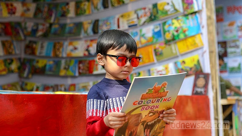 প্রতিবছরের মত এবারও একুশে বইমেলায় সাপ্তাহিক ছুটির দিন শুক্র ও শনিবার সকাল ১১টা থেকে দুপুর ১টা পর্যন্ত নির্ধারিত হয়েছে ‘শিশুপ্রহর’ হিসেবে। শনিবার একটি স্টলে পছন্দের বই খুঁজছে এক শিশু। ছবি: আসিফ মাহমুদ অভি