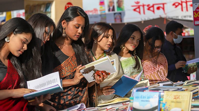 সবার পরনে শাড়ি, কেউ পরেছেন বাসন্তী রঙের, কেউবা লাল। কালো শাড়িতেও দেখা গেল অনেককে। সোমবার বইমেলার একটি স্টলে নারীরা।&amp;nbsp;ছবি: মাহমুদ জামান অভি