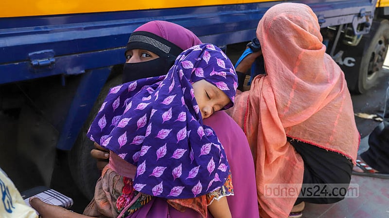 খাদ্যপণ্যের ঊর্ধ্বগতির মধ্যে ওএমএসের ট্রাক থেকে স্বল্পমূল্যে চাল ও আটা কিনতে আসা এক নারী। দীর্ঘ সময় অপেক্ষামান এই মায়ের কোলে ঘুমিয়ে পড়ে তার আদরের সন্তান। ছবি: আসিফ মাহমুদ অভি