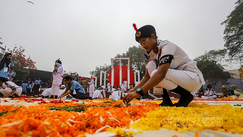 একুশে ফেব্রুয়ারির সকালে ফুলে ফুলে ভরে গেছে স্মৃতির মিনার, সেই ফুল সাজিয়ে রাখছেন স্বেচ্ছাসেবকরা। ছবি: আসিফ মাহমুদ অভি