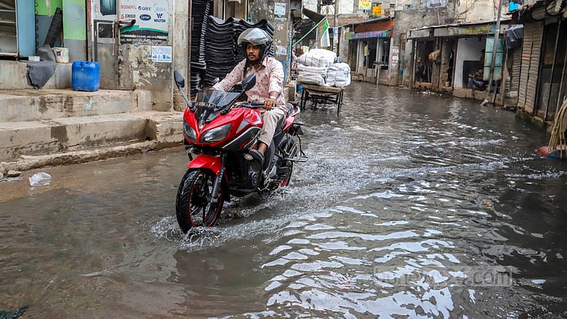 স্যুয়ারেজের ময়লা পানিতে তলিয়ে থাকা পুরান ঢাকার বংশালের মাজেদ সরদার রোডের সিক্কাটুলীতে বাইক চালিয়ে গন্তব্যে এক চালক। ছবি: আসিফ মাহমুদ অভি