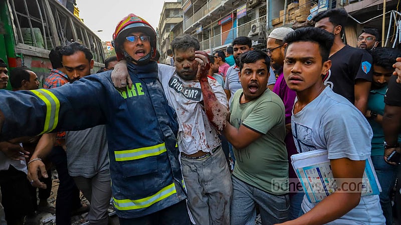 পুরান ঢাকার সিদ্দিক বাজারে মঙ্গলবার একটি ভবনে বিস্ফোরণে আহত একজনকে উদ্ধার করে নিয়ে যাচ্ছেন ফায়ার সার্ভিসের এক কর্মী ও স্থানীয়রা।&amp;nbsp;ছবি: আসিফ মাহমুদ অভি