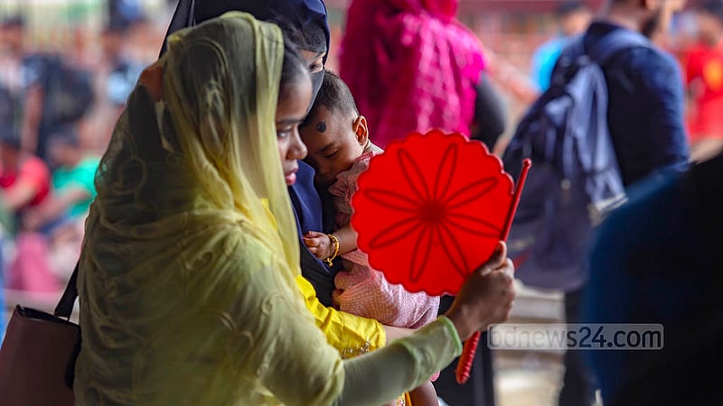 বিমানবন্দর রেলওয়ে স্টেশনে শুক্রবার সকালে গরম থেকে রক্ষায় এক শিশুকে পাখা দিয়ে বাতাস করা হচ্ছে।&amp;nbsp;ছবি: মাহমুদ জামান অভি