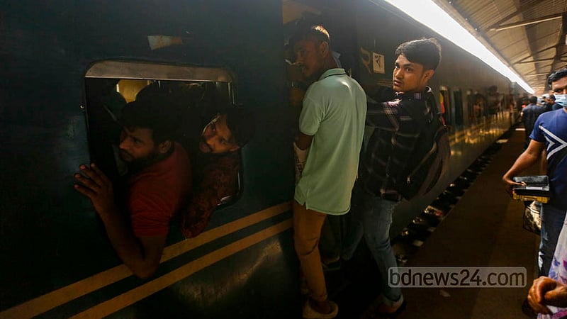 বিমানবন্দর রেলওয়ে স্টেশনে শুক্রবার সকালে ট্রেনের দরজার কোনোরকমে উঠে পড়েছেন তারা; ভেতরে ঢুকতে না পারায় ঝুলেই রওনা হয়েছেন বাড়ির পথে।&amp;nbsp;ছবি: মাহমুদ জামান অভি