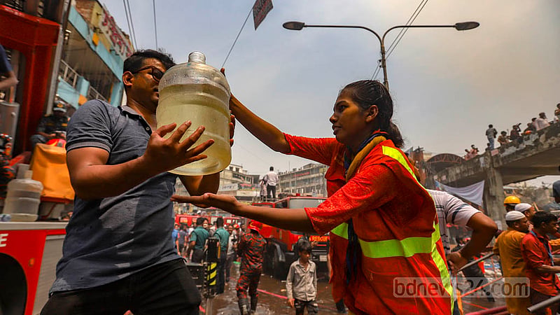 ঢাকার নিউ সুপার মার্কেটে আগুন নেভানোর কাজ করছে ফায়ার সার্ভিসের কর্মীরা, অন্য দিকে ফায়ার সার্ভিসের গাড়ি থেকে পানি নিয়ে ঢালছে স্বেচ্ছাসেবকেরা।&amp;nbsp;ছবি: মাহমুদ জামান অভি