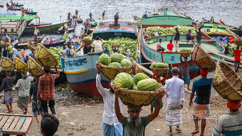 পুরান ঢাকার ওয়াইজঘাটে বুড়িগঙ্গা তীরের ট্রলার থেকে টুকরিতে করে তরমুজ তুলতে ব্যস্ত শ্রমিকরা।&amp;nbsp;ছবি: তাওহীদুজ্জামান তপু