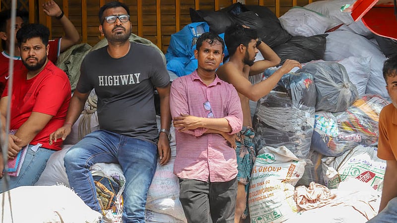 সড়কের উপর বস্তা ভরা সব দোকানের মালামাল, আগুন লাগার পর প্রাণপণ চেষ্টায় সেসব বের করেছেন দোকানিরা। তারপর দিনভর বস্তার উপর বসে অপেক্ষা আগুন নেভার খবর শুনতে।&amp;nbsp;ছবি: আসিফ মাহমুদ অভি