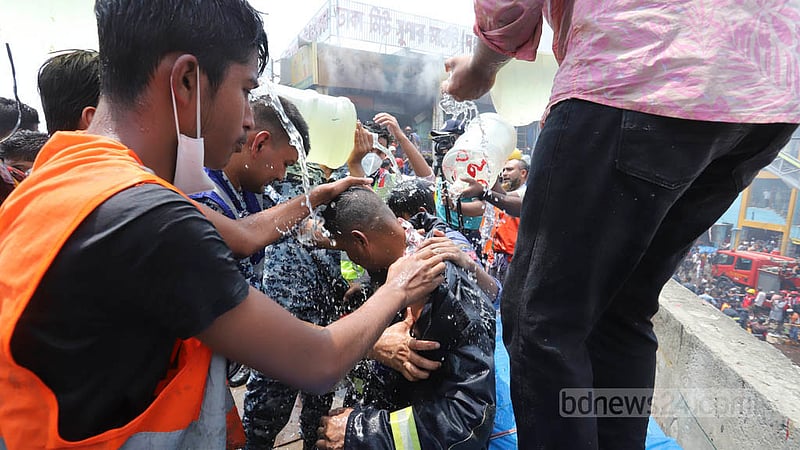নিউ সুপার মার্কেটে আগুন নেভাতে গিয়ে গরম ও আগুনের তাপ থেকে নিস্তার পেতে মাথায় পানি ঢালছেন ফায়ার সার্ভিসের কর্মীরা।&amp;nbsp;ছবি: আসিফ মাহমুদ অভি