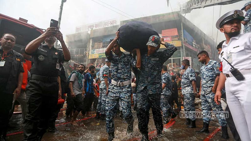 নিউ সুপার মার্কেটে আগুন লাগার পর নেভানোর কাজ করছে ফায়ার সার্ভিসের কর্মীরা; অন্যদিকে দোকানের মালামাল সরাতে সাহায্য করছে আইনশৃঙ্খলা বাহিনী।&amp;nbsp;ছবি: তাওহীদুজ্জামান তপু