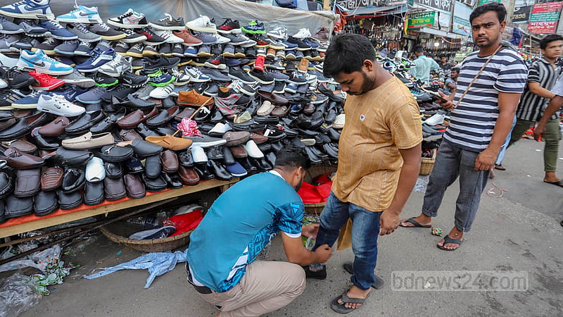 ফুটপাতে বসা জুতার দোকানে ঈদের জুতা দেখছেন এক ক্রেতা। ছবি: আসিফ মাহমুদ অভি
