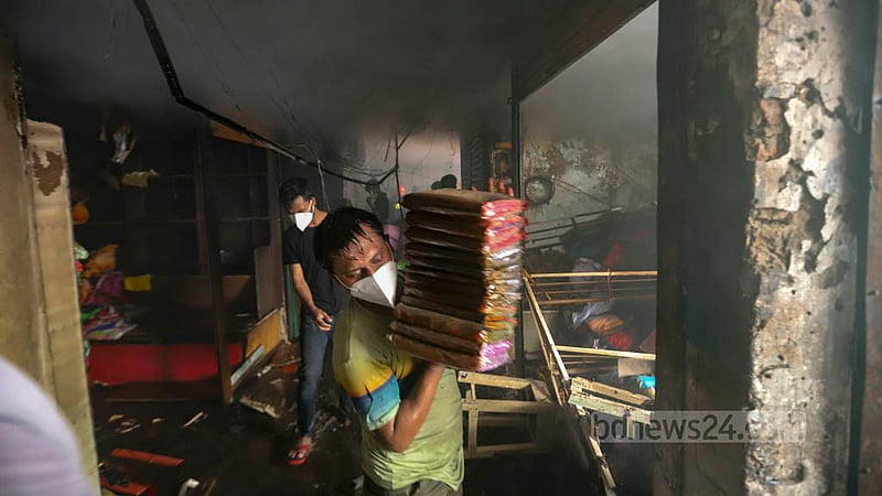 নিউ সুপার মার্কেটের তিন তলায় আগুনের সূত্রপাত; আগুন কিছুটা নিয়ন্ত্রণে আসার পর দোকানিরা মালামাল বের করছে দোকান থেকে।&amp;nbsp;ছবি: মাহমুদ জামান অভি