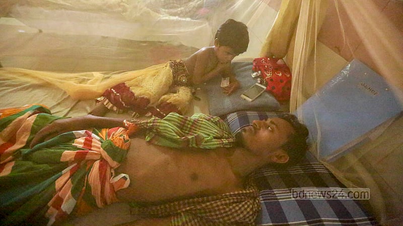 ঢাকার মুগদা মেডিকেল কলেজ হাসপাতালে মশারির ভেতরে ডেঙ্গু আক্রান্ত বাবার মাথার কাছে বসে সময় পার করছে এক শিশু।&amp;nbsp;ছবি: তাওহীদুজ্জামান তপু﻿