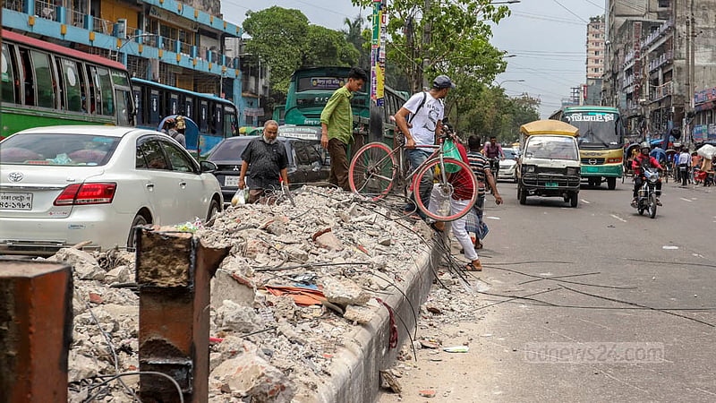 নিউ মার্কেটের সামনের পুরোনো ফুটওভার ব্রিজের ভাঙা অংশ দিয়ে সাইকেল নিয়ে সড়ক পার হচ্ছেন একজন। ছবি: আসিফ মাহমুদ অভি