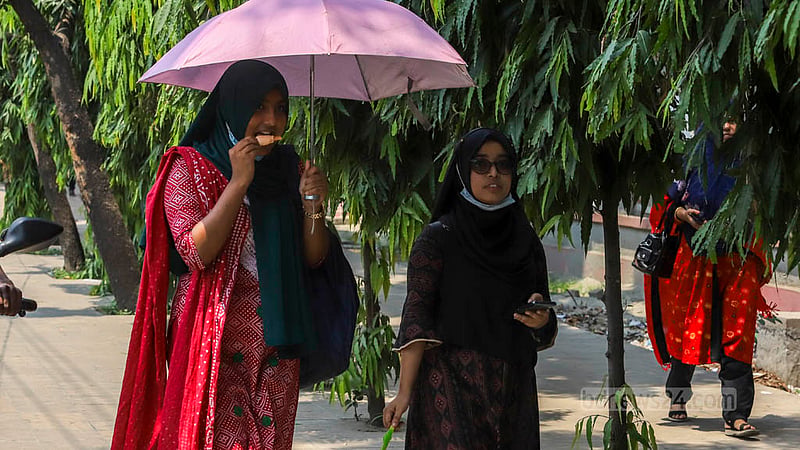 গরমের মধ্যে ছাতা মাথায় বুধবার তেজগাঁওয়ে আইসক্রিম হাতে গন্তব্যে দুই শিক্ষার্থী।&amp;nbsp;ছবি: আসিফ মাহমুদ অভি