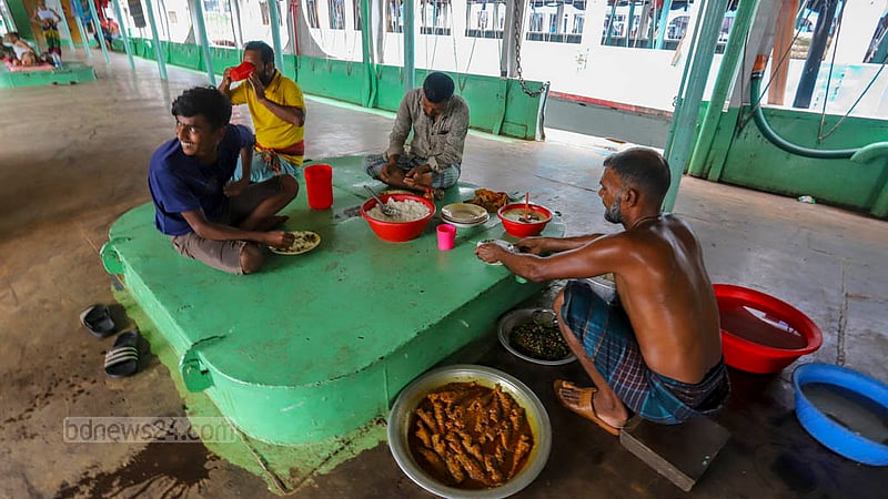ঘূর্ণিঝড় ‘মোখা’র প্রভাব বাড়ায় দেশের দক্ষিণাঞ্চলের জেলাগুলোতে শনিবার ছেড়ে যায়নি কোনো লঞ্চ। বন্ধ থাকায় ব্যস্ততা নেই শ্রমিকদের, দুপুর বেলা একসঙ্গে খাবার খাচ্ছিলেন তাদের কয়েকজন। ছবি: আসিফ মাহমুদ অভি