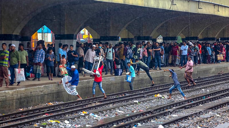 ঢাকার কমলাপুর রেল স্টেশনে বুধবার&amp;nbsp; বৃষ্টিতে ট্রেনের অপেক্ষায় ঈদে বাড়িমুখো যাত্রীরা।