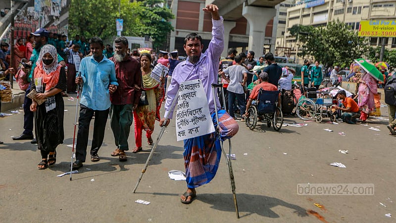 ঢাকার শাহবাগে জাতীয় জাদুঘরের সামনের সড়কে বিভিন্ন দাবিতে গলায় প্ল্যাকার্ড ঝুলিয়ে অবস্থান কর্মসূচিতে অংশ নেওয়া একজন।&amp;nbsp;&amp;nbsp;ছবি: তাওহীদুজ্জামান তপু