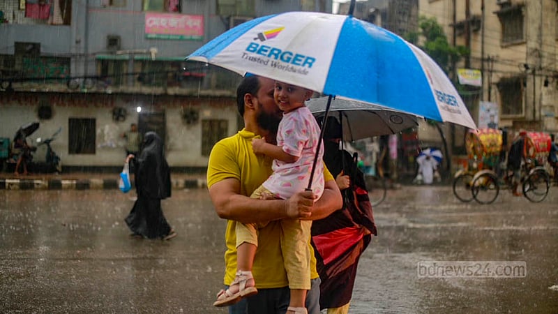 ঢাকার মোহাম্মদপুরে শুক্রবার মুষলধারে বৃষ্টির মধ্যে সস্তানকে কোলে নিয়ে ছাতা হাতে এক বাবা।&amp;nbsp;ছবি: তাওহীদুজ্জামান তপু