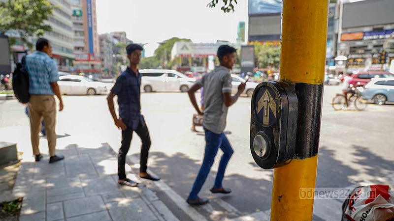 রাস্তা পারাপারের জন্য সড়কের পাশে ফুটপাতে আছে ‘স্মার্ট’ ট্রাফিক লাইট সিস্টেম। কিন্তু সেই পুশ বাটনে চাপ দেওয়ার যেন সময় নেই পথচারীদের। নিজেদের ইচ্ছেমত পারাপার হচ্ছেন তারা।&amp;nbsp;ছবি: মাহমুদ জামান অভি