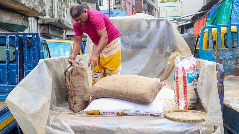 মোহাম্মদপুর কৃষি মার্কেটে বৃষ্টির পানি ঢুকে ভিজে যাওয়া চাল একটি ট্রাকের উপরে শুকাতে দিচ্ছে একজন। ছবি: আসিফ মাহমুদ অভি