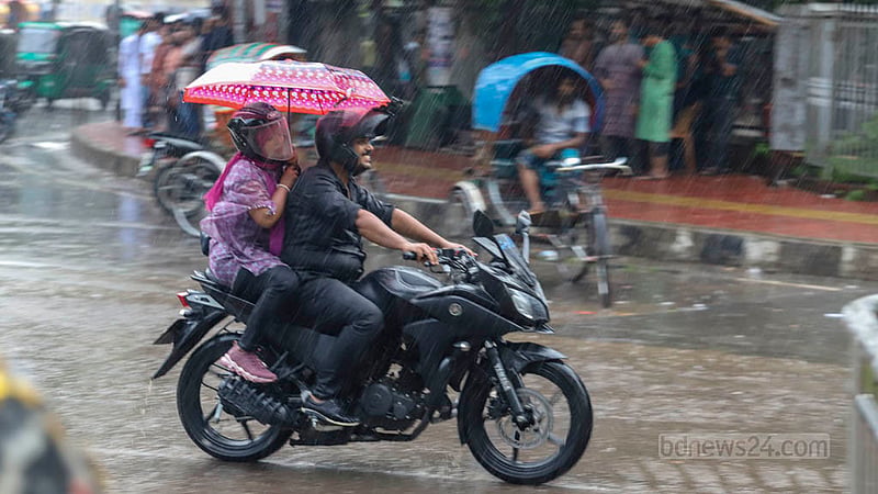 ঢাকার টিএসসিতে শুক্রবার বিকেলে বৃষ্টির মধ্যে ছাতা মাথায় এক মোটরসাইকেল চালক ও আরোহী। ছবি: আসিফ মাহমুদ অভি