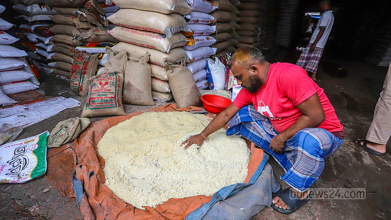 ভারি বর্ষণে মোহাম্মদপুর কৃষি মার্কেটে চালের আড়তে ভিজে যাওয়া চাল শুকাতে দিয়েছেন এক দোকানি। ছবি: আসিফ মাহমুদ অভি