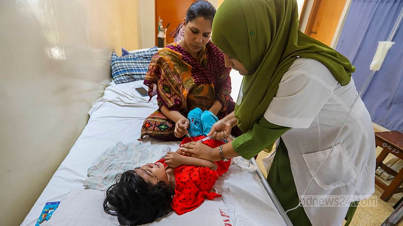 ঢাকার মগবাজার হলি ফ্যামিলি রেড ক্রিসেন্ট হাসপাতালে রোববার ডেঙ্গু আক্রান্ত শিশু শাহনুজার সেবায় ব্যস্ত এক সেবিকা। তিন দিন ধরে ভর্তি হয়ে চিকিৎসা নিচ্ছে পুরান ঢাকার এই শিশুটি। ছবি: আসিফ মাহমুদ অভি