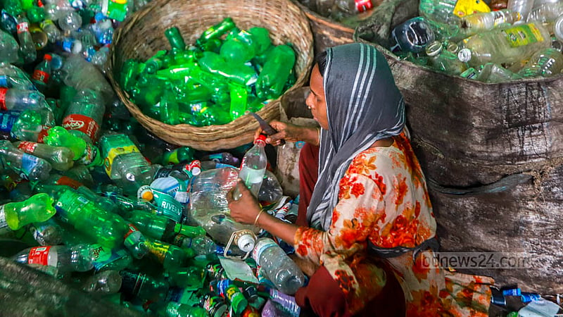 প্রক্রিয়াজাতকরণ কারখানায় প্লাস্টিকের বোতল থেকে মোড়ক সরাচ্ছেন এই নারী শ্রমিক।&amp;nbsp;ছবি: তাওহীদুজ্জামান তপু