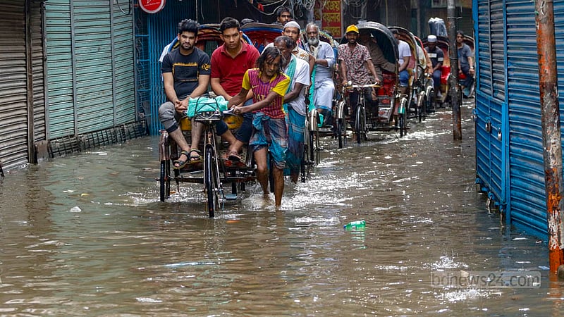 পুরান ঢাকার আলু বাজার এলাকায় শুক্রবার দুপুরে বৃষ্টিতে জলাবদ্ধতা হলে তার মধ্যে দিয়ে রিকশায় যাত্রী নিয়ে গন্তব্যে চালকেরা।
