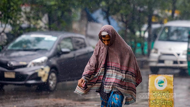 ঢাকার সবুজকাননে মঙ্গলবার দুপুরে বৃষ্টির মধ্যে গামছা মাথায় এক ব্যক্তি।&amp;nbsp;ছবি: মাহমুদ জামান অভি