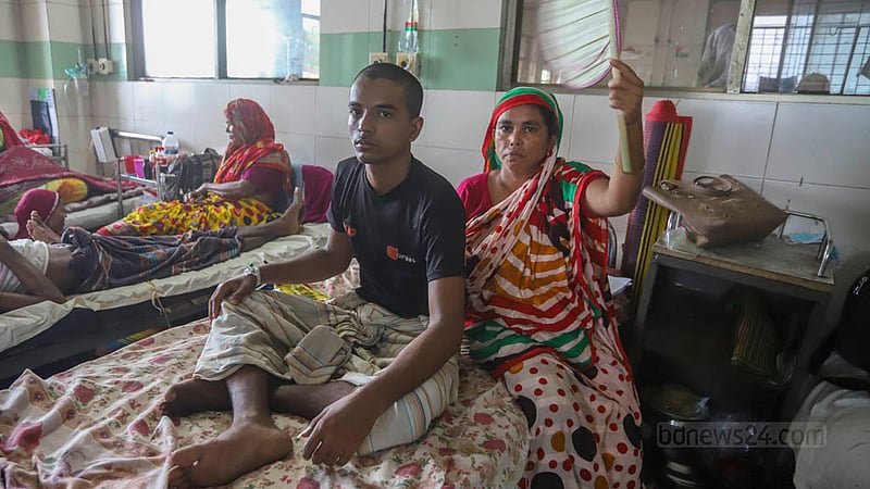 রাজবাড়ী জেলার নাসিম মৃধা ডেঙ্গু আক্রান্ত হয়ে তিন দিন ধরে ঢাকা মেডিকেল কলেজ হাসপাতালে ভর্তি হয়ে চিকিৎসা নিচ্ছেন। ছেলের সেবায় পাশেই বসে আছে মা। ছবি: আসিফ মাহমুদ অভি