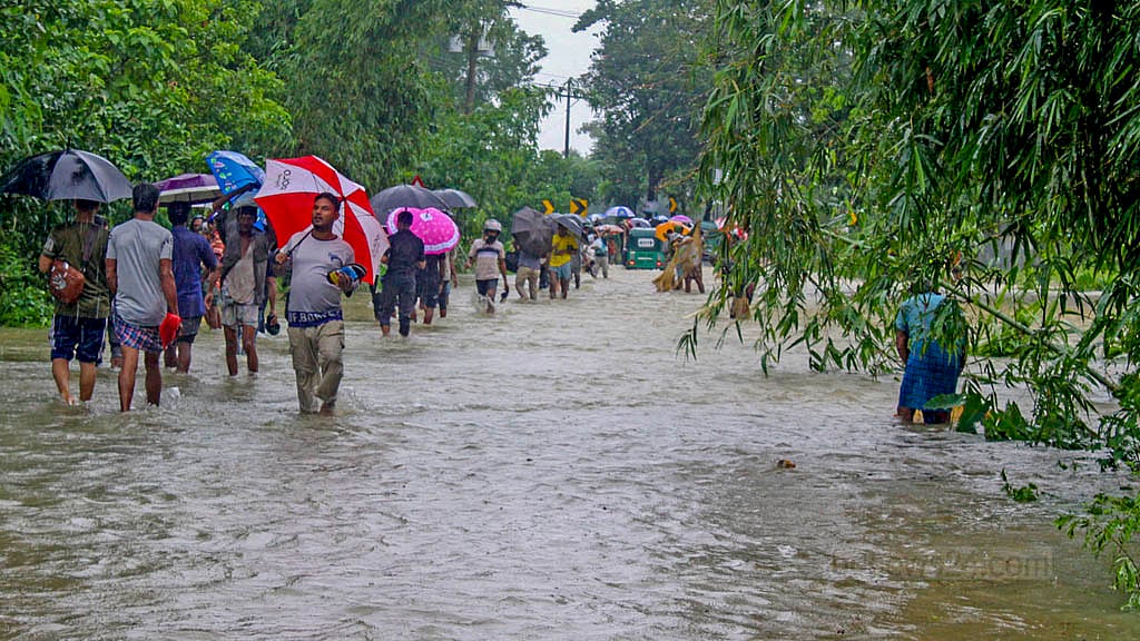 চট্টগ্রাম-কক্সবাজার মহাসড়কের চন্দনাইশের হাশিমপুর এলাকায় সড়কে হাঁটুর উপরে পানি, তার মধ্য দিয়ে হেঁটে যাচ্ছে মানুষ।&nbsp;