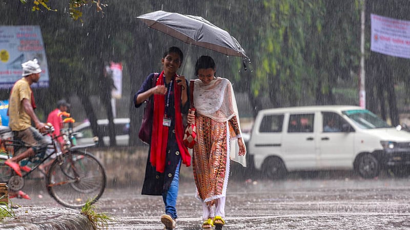 ঢাকা বিশ্ববিদ্যালয়ের টিএসসি এলাকায় বৃহস্পতিবার দুপুরে বৃষ্টিতে ছাতা হাতে দুই তরুণী।&amp;nbsp;ছবি: তাওহীদুজ্জামান তপু