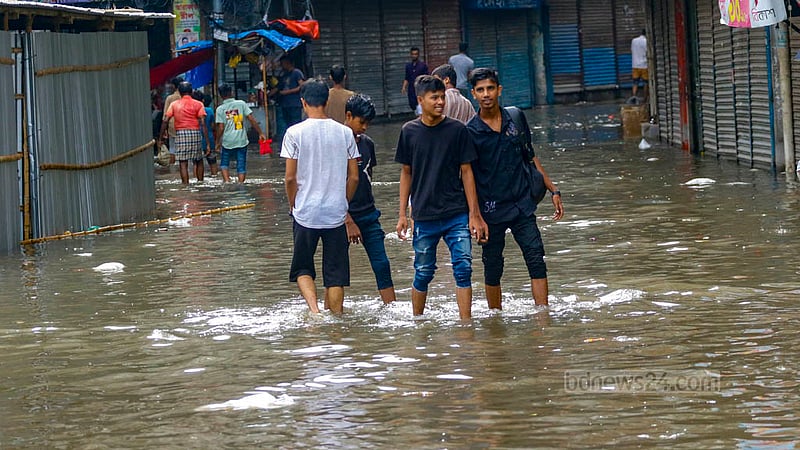 পুরান ঢাকার নাজিরা বাজারে শুক্রবারে কয়েক ঘণ্টার বৃষ্টিতে তলিয়ে যায় রাস্তা। তার মধ্যে দিয়ে যাতায়াত করছে মানুষ।